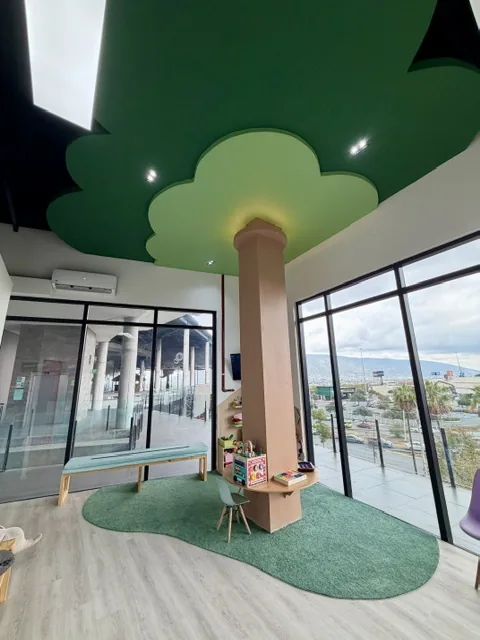 Área de espera infantil con diseño de árbol dentro de la clínica