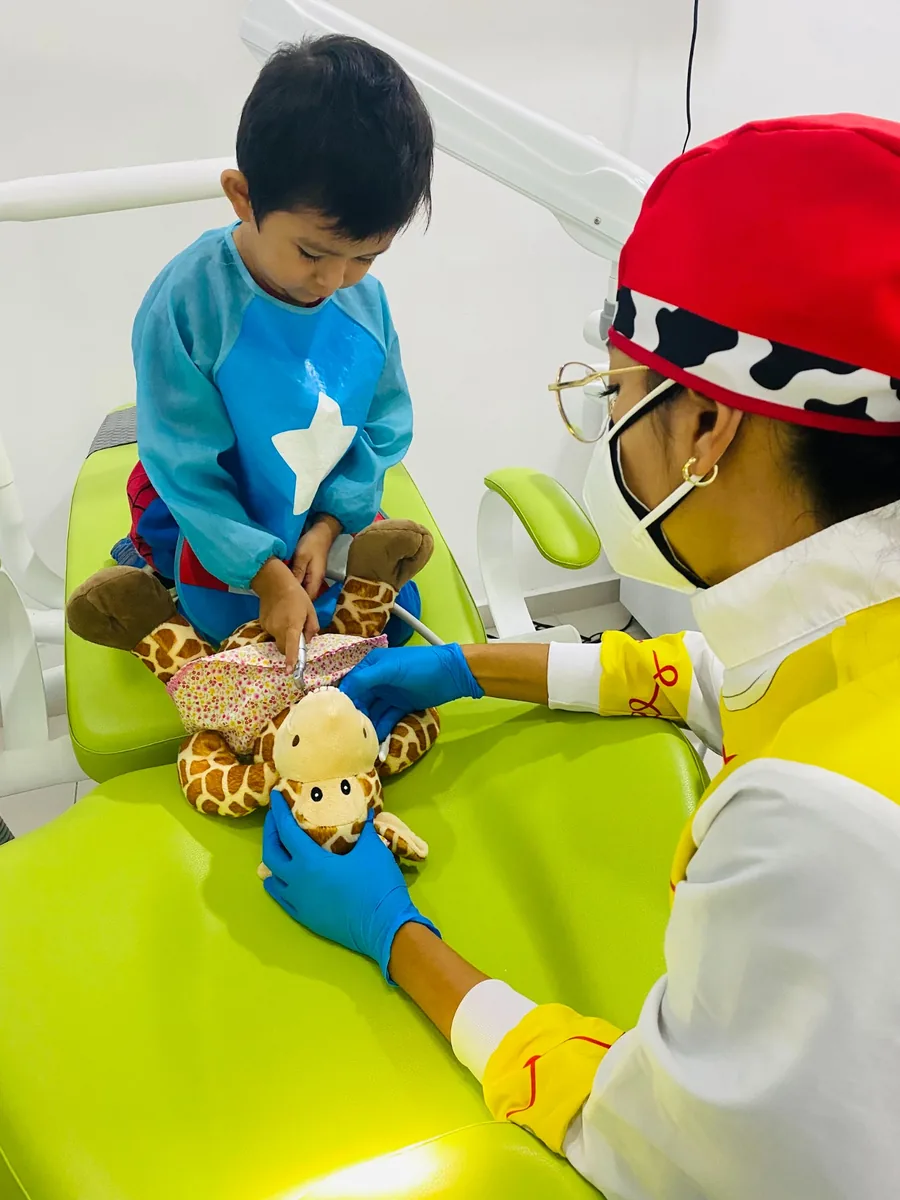 Niño aprendiendo a cepillar un peluche durante la consulta